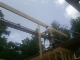 Carpenter setting a ridge beam over a new addition frame — Ice Dam Removal by Roofing Brothers in Butner