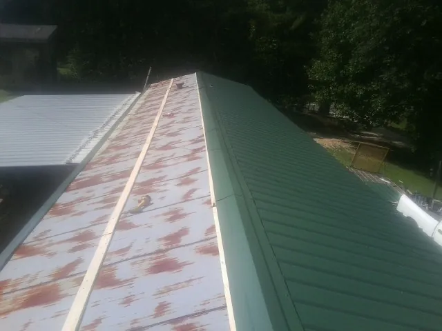 Old rusted panels beside newly installed green metal roofing — Wind Damage Roof Repair by Roofing Brothers in Butner