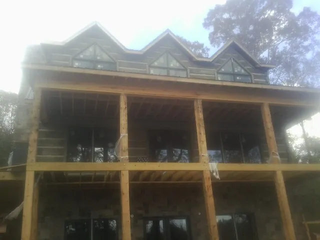 Dormers and porch framing on a large log home under construction — Roof Coating work by our crew in Butner