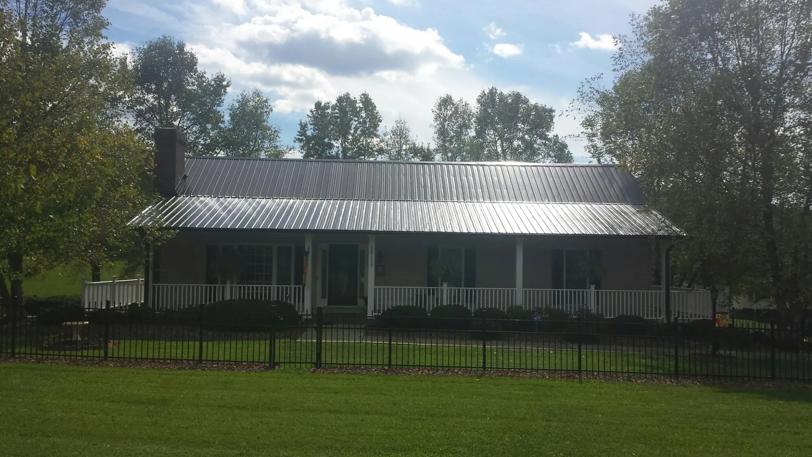 Gray metal roof on a brick ranch with a full width front porch — Gutter Guard Installation work by our crew in Butner