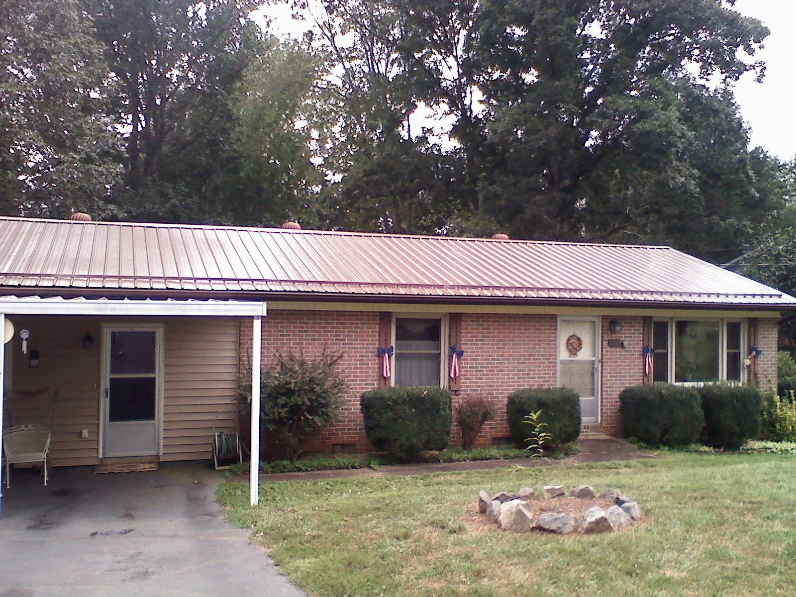 Bronze metal roof and carport on a brick ranch home — Roof Repair work by our crew in Butner